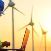 people - 2 workers looking at laptop in front of windmills at sunset